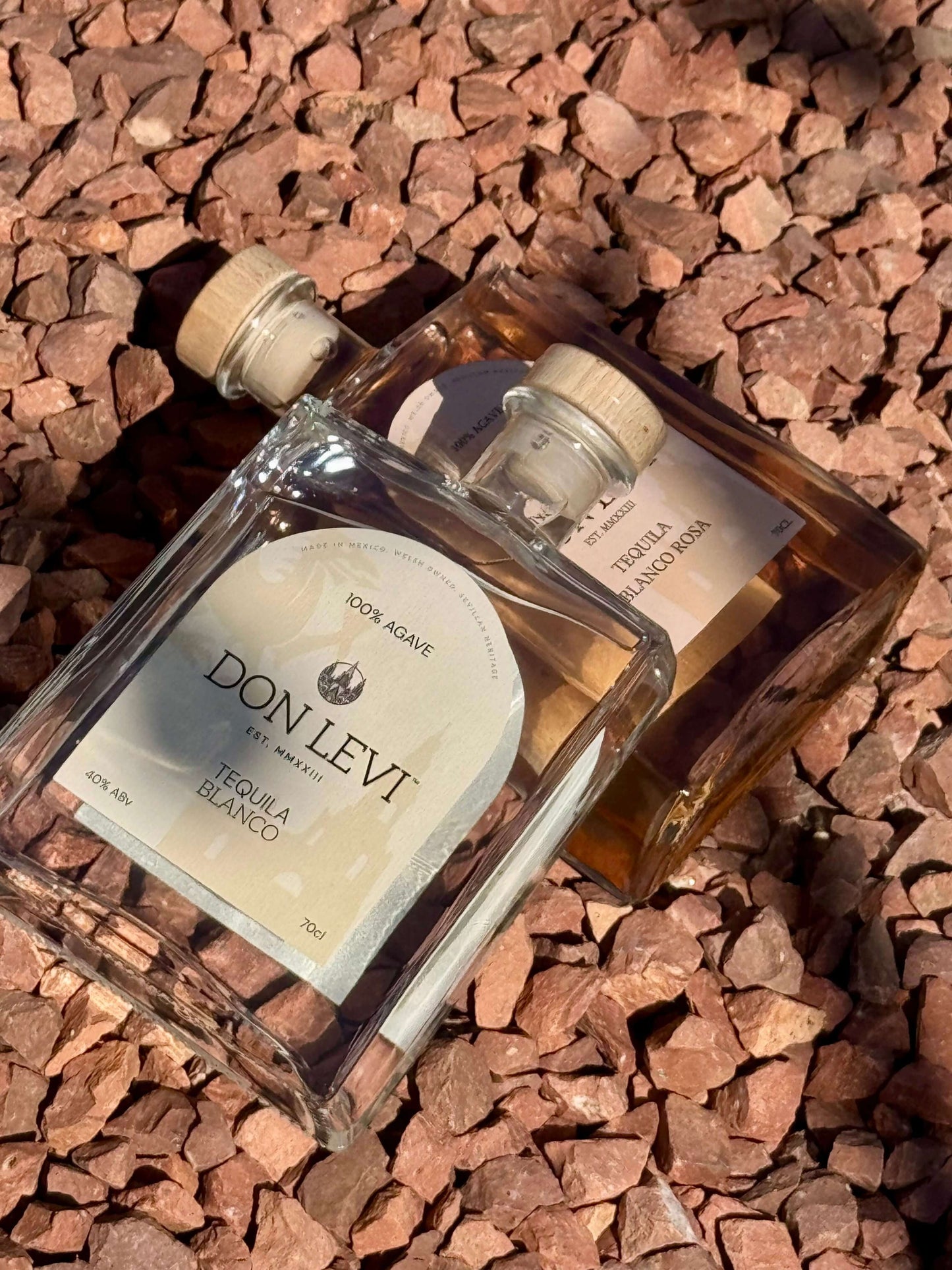 A bottle of Don Levi Blanco & Don Levi Rosa on a bed of stones.