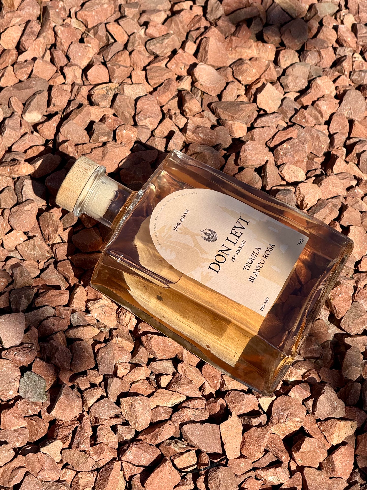 Bottle of Don Levi tequila on a bed of red stones