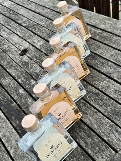 3 bottles of Don Levi Blanco & Rosa on a wooden, weathered table.